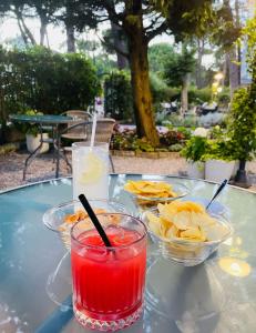 a table with two bowls of chips and a drink at Hotel B&B Des Bains Milano Marittima in Milano Marittima