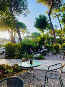 eine Terrasse mit einem Tisch, Stühlen und Bäumen in der Unterkunft Des Bains 138 B&B in Milano Marittima