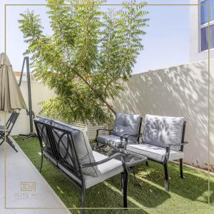 Impressive 3BR Villa-Akoya في دبي: كرسيين وشجرة على فناء