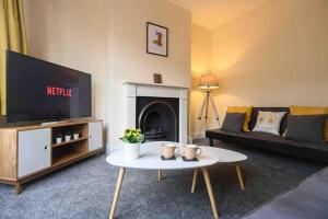 a living room with a tv and a couch and a table at Beechwood House by Tŷ SA - ICC & Celtic Manor in Newport