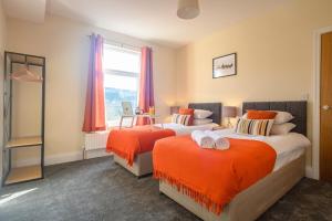 um quarto com 2 camas com lençóis laranja e uma janela em Beechwood House by Tŷ SA - ICC & Celtic Manor em Newport