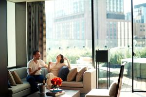 a man and woman sitting on a couch in a living room at The Gate Hotel Tokyo by Hulic in Tokyo