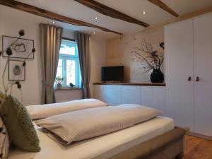 a bedroom with two beds and a tv on the wall at Ferienwohnungen Schneider in Lennestadt