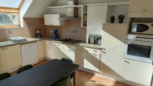 Una cocina con gabinetes blancos y una mesa en ella. en Ref 089 Maison standing avec jardin et internet pour dix, en Arzon 8 fotos más
