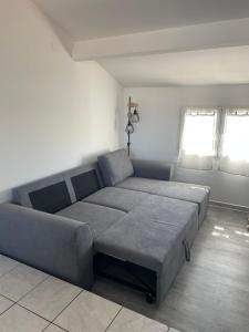 a large couch in a living room with two windows at Appartement des Ponts Bleus in Martigues