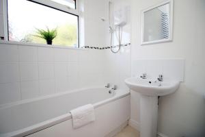 a white bathroom with a sink and a tub and a mirror at Bellevue by Tŷ SA - Modern 3 bed in Newport in Newport