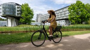 Eine Frau in einem Kleid, die Fahrrad fährt. in der Unterkunft Kongresshotel Potsdam am Templiner See in Potsdam