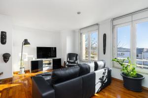 a living room with a black leather couch and a tv at WHome Cosy Urban Hideaway in Belém with River View in Lisbon