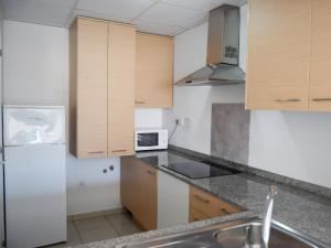 eine Küche mit Holzschränken und einem weißen Kühlschrank in der Unterkunft Apartamentos Benicarló Lowcost 3000 in Benicarló