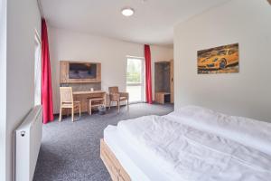 Schlafzimmer mit einem Bett, einem Schreibtisch und einem Tisch in der Unterkunft Hotel am Interpark in Großmehring