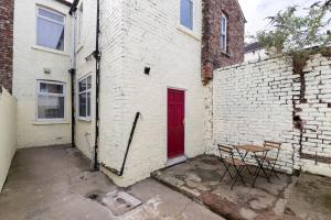 a red door on a white brick building with a table at Comfortable & very spacious home in Stockton-on-Tees