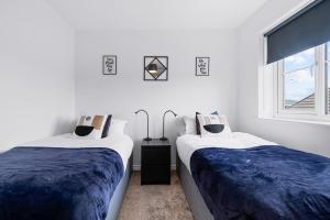 two beds in a white room with a window at Bridge House by Tŷ SA in Newport