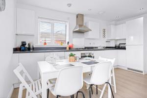 a white kitchen with a white table and chairs at Bridge House by Tŷ SA in Newport