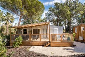 ein kleines Haus mit einer Veranda und einer Terrasse in der Unterkunft Camping L'Oasis et California in Le Barcarès