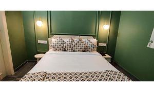 1 dormitorio con 1 cama grande y paredes verdes en FabHotel Niraant, en Surat