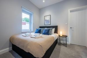 a bedroom with a large bed with blue pillows and a window at Brynglas House by Tŷ SA in Newport