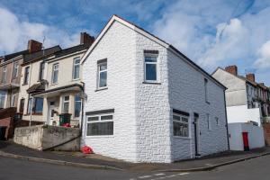 uma casa de tijolos brancos ao lado de uma rua em Brynglas House by Tŷ SA em Newport