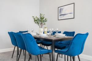 a dining room with a table with blue chairs at Brynglas House by Tŷ SA in Newport