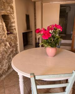 un tavolo con un vaso con fiori rossi sopra di Domaine du Cruvelet Grand gite a Trigance