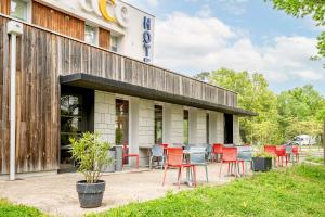 un bâtiment avec des tables et des chaises à l'extérieur dans l'établissement Ace Hotel Bordeaux Cestas, à Cestas