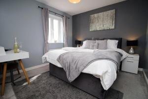 a bedroom with a large bed and a window at Buxton Way by Tŷ SA - 3 bedroom house in Royal Wootton Bassett