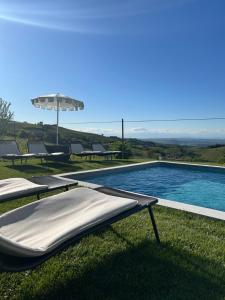 a swimming pool with two beds and an umbrella at Borgo Piani - Camere di Charme in Mango