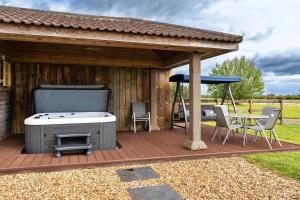 una terrazza in legno con griglia, tavolo e ombrellone di Finest Retreats - Stone Bow Farmhouse a Weston-super-Mare