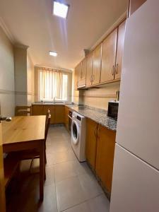 a kitchen with a table and a washing machine at UIM Mediterraneo Churruca Wifi in Puerto de Sagunto