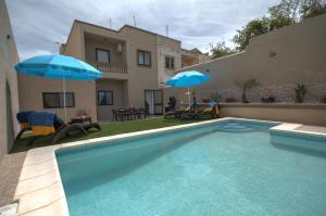 a swimming pool with two blue umbrellas and a house at Villa Sunview in Rabat