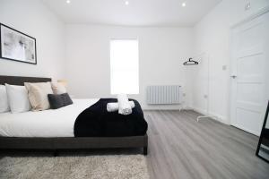 a white bedroom with a bed and a lamp at Modern 1 Bedroom - Caxton Place by Tŷ SA in Newport