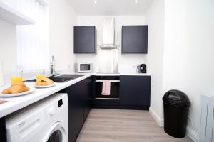 cocina blanca con fregadero y lavavajillas en Modern 1 Bedroom - Caxton Place by Tŷ SA en Newport