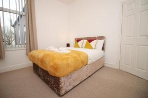 um quarto com uma cama com um cobertor amarelo em Camelot House by Tŷ SA em Newport