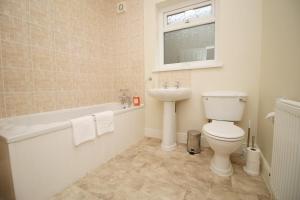 a bathroom with a toilet and a sink and a bath tub at Camelot House by Tŷ SA in Newport