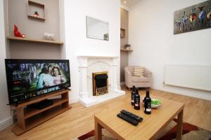 uma sala de estar com televisão e lareira em Camelot House by Tŷ SA em Newport