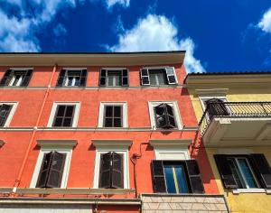 ein hohes rotes Gebäude mit weißen Fenstern an einer Straße in der Unterkunft AGATHEA APARTMENT - Central Location, Just 50m from the Sea - Nettuno in Nettuno
