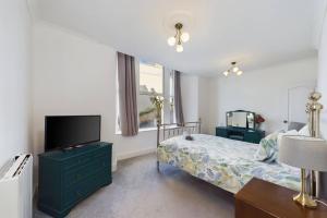 um quarto com uma cama e uma televisão de ecrã plano em Loveliest Homes Torquay - 3 bed, 2 bathroom, balcony, parking em Torquay