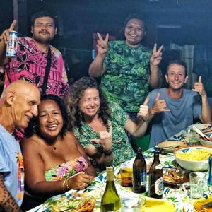 un gruppo di persone che posano per una foto a un tavolo di CHAMBRE CHEZ TAPUHERE LODGE a Fare (Huahine Nui)