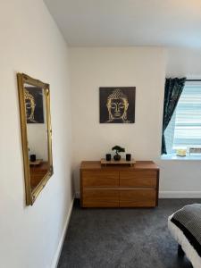 a bedroom with a dresser and a mirror on the wall at 3-Bed House, Birmingham in Birmingham