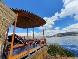 ein Boot mit einem Stuhl und einem Regenschirm auf dem Wasser in der Unterkunft Uros Titicaca UMA lodge in Puno