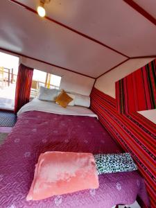 ein großes Bett in einem Zelt mit lila Laken in der Unterkunft Uros Titicaca UMA lodge in Puno