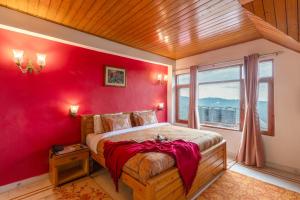 Alaya Stays Meridian Oak 5BHK Villa in Shimla في شيملا: غرفة نوم حمراء مع سرير بجدار احمر
