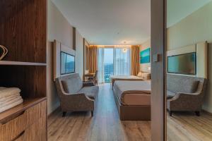 Panorama Superview Nha Trang Apartment في نها ترانغ: غرفه فندقيه بسرير وكرسيين