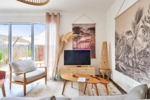 a living room with a tv and a couch and a table at Maison pour 4 - jardin - 600m de la plage in Barbâtre