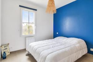 a blue and white bedroom with a bed and a window at Maison pour 4 - jardin - 600m de la plage in Barbâtre