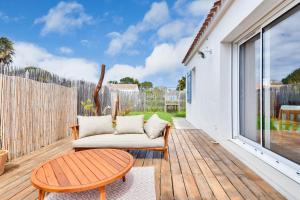 a patio with a couch and a table at Maison pour 4 - jardin - 600m de la plage in Barbâtre