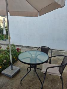 einem Glastisch und einem Stuhl unter einem Schirm in der Unterkunft Apartmani Jovanovic in Bar