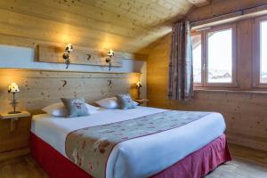 een slaapkamer met een bed in een houten hut bij Chalet-Hôtel Le Beausoleil, The Originals Relais (Hotel-Chalet de Tradition) in La Toussuire