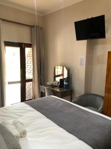 a bedroom with a bed with a television on the wall at Serene Guesthouse in Middelburg