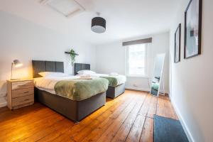 a bedroom with two beds and a wooden floor at Chapel Lodge by Tŷ SA in Newport