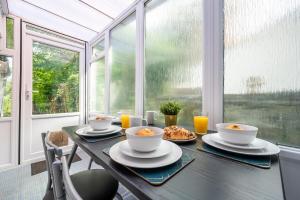 a table with bowls and plates of food on it in front of a window at Chapel Lodge by Tŷ SA in Newport